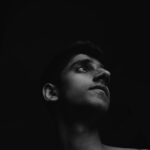 Striking black and white portrait of a young man looking upward, showcasing a pensive mood.